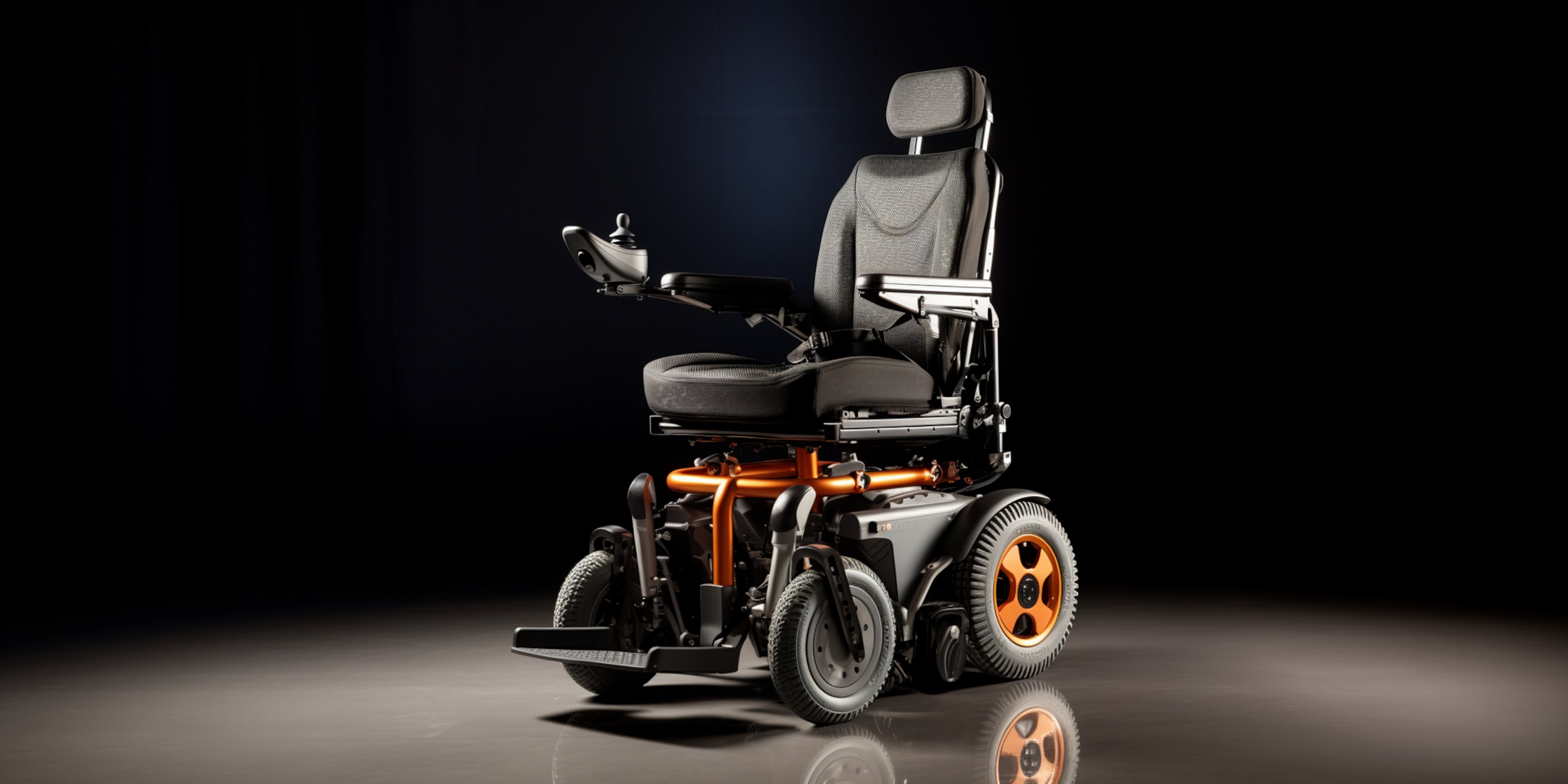 A high-end electric wheelchair with a black and gray seat, orange mechanical accents, and orange-rimmed wheels, photographed on a reflective dark studio floor against a black background.