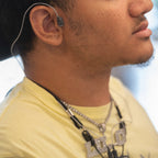 gray wire wrapped around the ear of a person in a light yellow t-shirt.