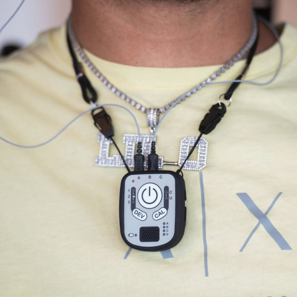 A close-up of a person wearing a Kinemo Connect controller on a necklace over a light yellow t-shirt.