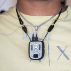 A close-up of a person wearing a Kinemo Connect controller on a necklace over a light yellow t-shirt.