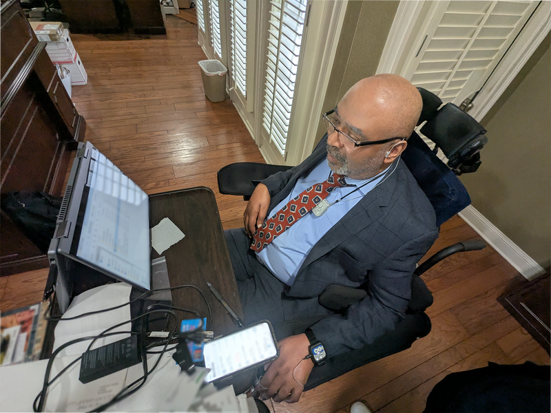 Man in a wheelchair using technology in a home office setting