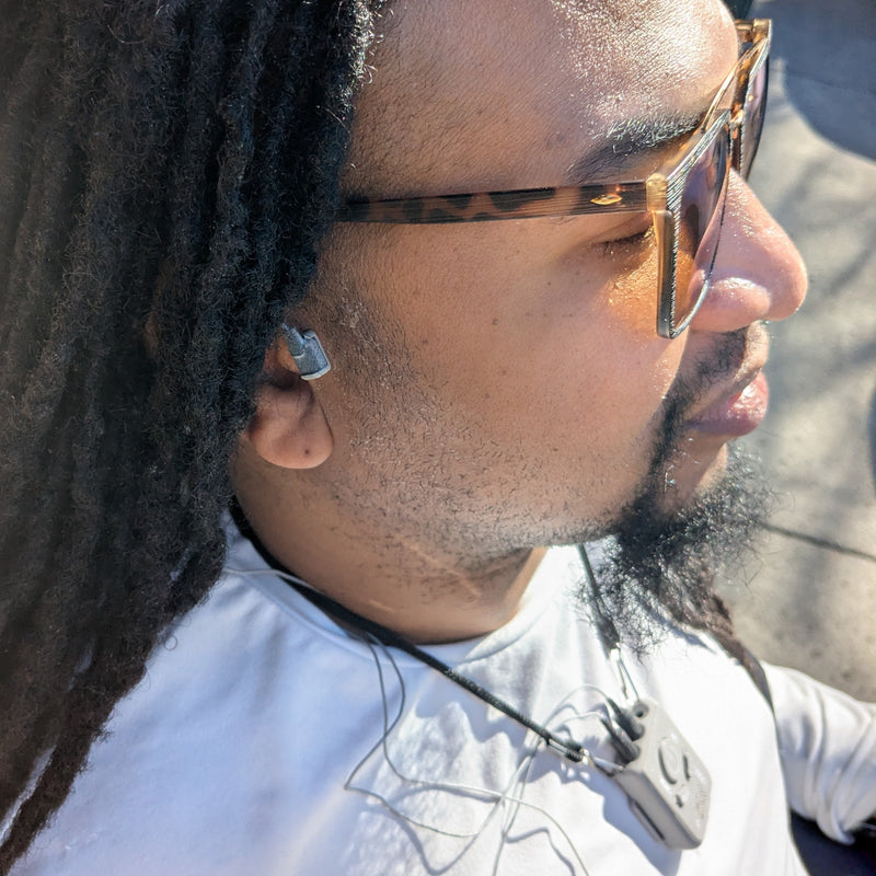 Person wearing sunglasses and a white shirt with a blurred background